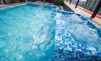 a large , empty swimming pool with blue tiles and white water is surrounded by a wooden deck at Villa Baron