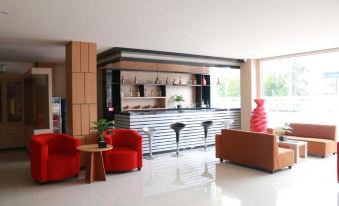 a modern hotel lobby with a bar area , featuring red chairs and a leather couch at Grand Dian Hotel Brebes