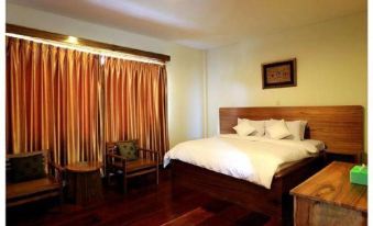 a bedroom with a wooden bed , a chair , and a tv . also a potted plant in the room at Hotel Grand Papua Fakfak