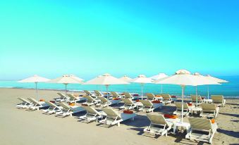 a sandy beach with several lounge chairs and umbrellas set up on the sandy shore at Grecotel Plaza Beach House