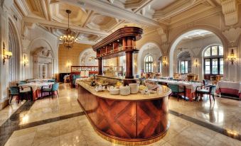 a large , well - lit restaurant with marble floors and high ceilings , featuring a bar area with multiple tables and chairs at The Phoenicia Malta