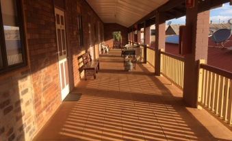 a long , covered walkway with brick walls and a tiled floor , leading to a building at Hotel Corones