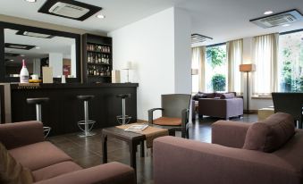 a modern living room with comfortable seating , a bar area , and a dining table in the background at Hotel Touring