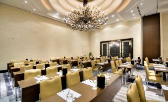 a large conference room with rows of chairs and tables , a chandelier hanging from the ceiling at AX The Palace