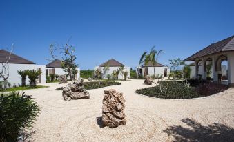 a courtyard surrounded by small buildings , with a rock garden in the center and trees surrounding the area at The Residence Zanzibar