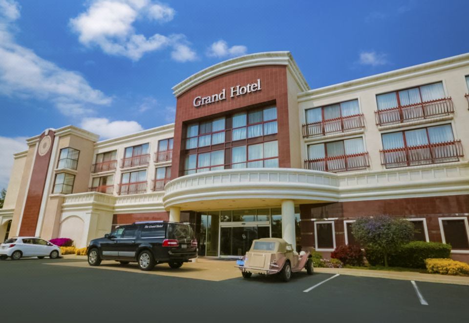 a large hotel with a red and white building , featuring a car parked in front of it at Grand Hotel