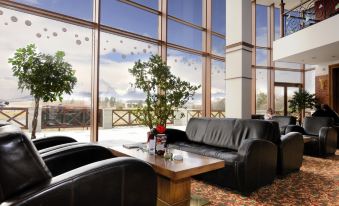a modern lounge area with a black leather couch , wooden coffee table , and large windows overlooking the outdoors at Hotel International