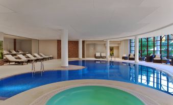 a large indoor swimming pool surrounded by chairs and tables , providing a relaxing atmosphere for guests at Sheraton Mallorca Arabella Golf Hotel