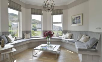 a living room with large windows , a glass coffee table , and a bench , along with cushions and pillows at Watersmeet Hotel