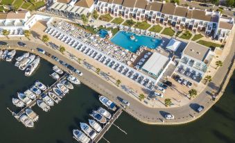 aerial view of a marina with multiple boats docked in the water , surrounded by buildings and a parking lot filled with numerous boats at Lago Resort Menorca Casas del Lago