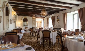 a large dining room with wooden beams on the ceiling , white tablecloths , and numerous chairs arranged around tables at Hôtel Saint-Martin - la Maison Younan
