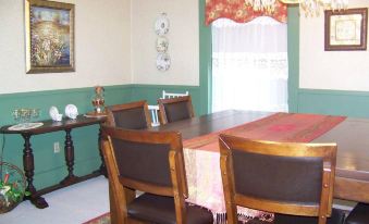 a dining room with a wooden dining table surrounded by chairs , and a couch in the background at Barclay Bed and Breakfast