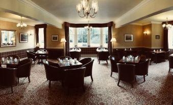 a large , well - lit room with several tables and chairs arranged for a formal dining experience at Dryburgh Abbey Hotel