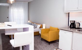 a living room with a couch , chair , and dining table in front of a kitchen at La Palmera Rooms