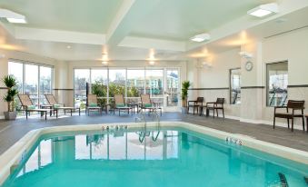 an indoor swimming pool with a view of the city , surrounded by chairs and tables at Courtyard Yonkers Westchester County