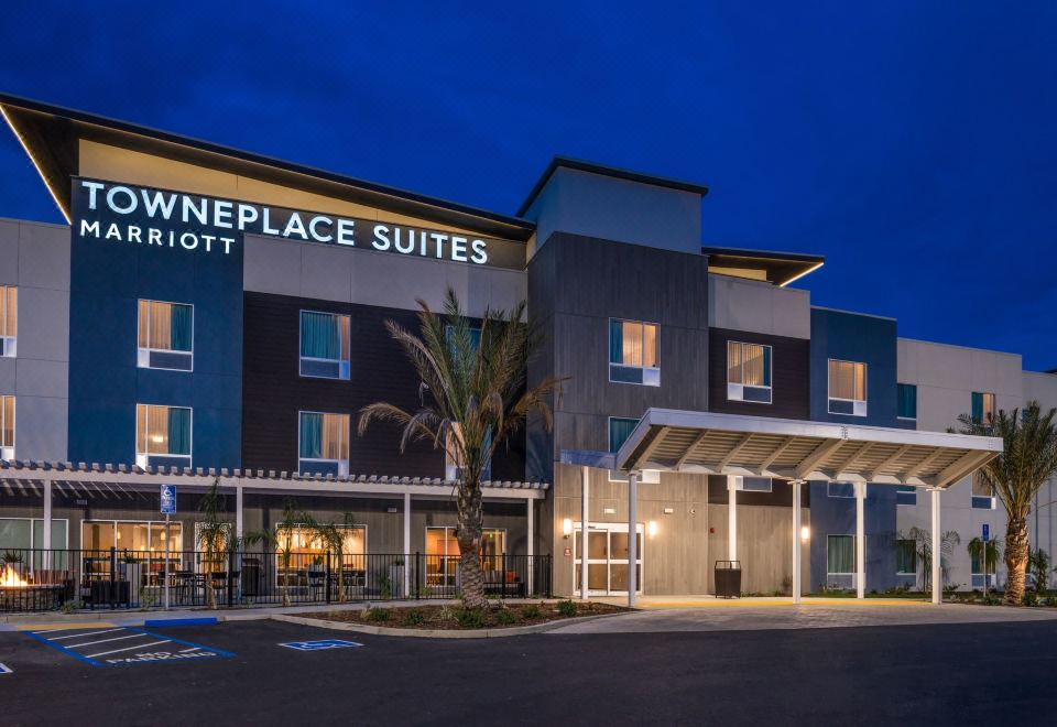 "a modern hotel building with the name "" the overplace suites "" displayed on it , under the moonlight" at TownePlace Suites Merced