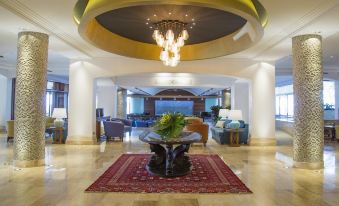 a hotel lobby with a marble floor , a large chandelier hanging from the ceiling , and several potted plants placed around the room at Columbia Beach Resort