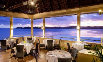 a dining room with tables and chairs set up for a formal meal , overlooking a beautiful view of the ocean at Shangri-La Yanuca Island, Fiji