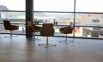 a room with three chairs and a table in front of a large window overlooking a cityscape at Self Check-in Hotel Von Rotz