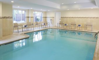 a large swimming pool with clear water and several chairs around it in an indoor setting at SpringHill Suites Atlanta Six Flags