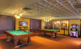 a game room with two pool tables , a television , and a bar , creating a cozy atmosphere at Wellsworth Hotel