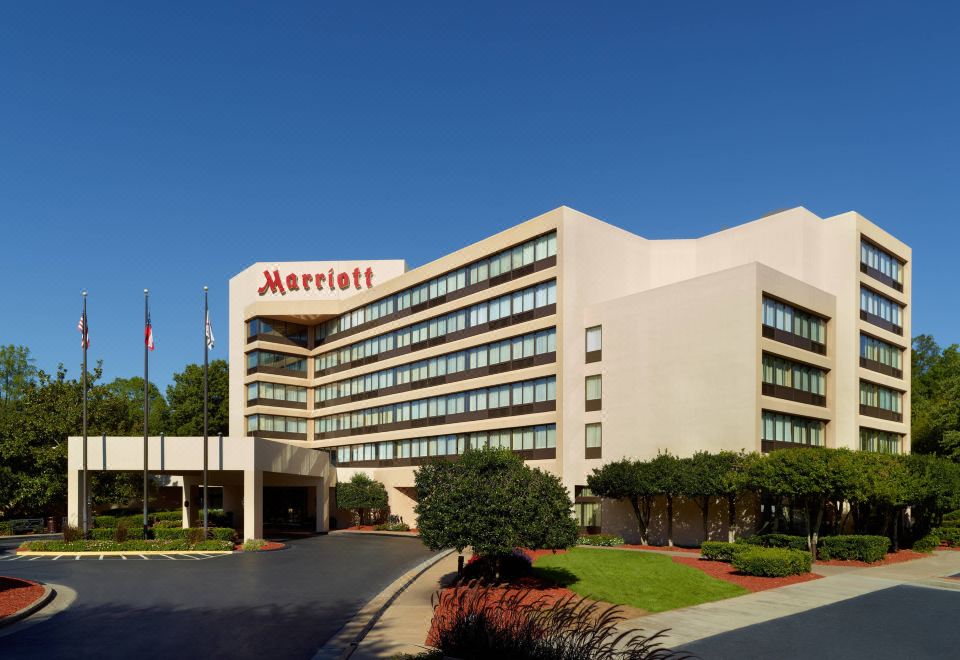 "a large hotel with a red sign that reads "" marriott "" prominently displayed on the front of the building" at Atlanta Marriott Peachtree Corners