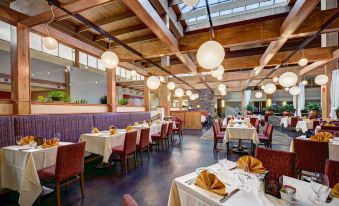 a large , modern restaurant with wooden tables and chairs , multiple hanging lights , and a bar area at Crowne Plaza Suffern-Mahwah, an IHG Hotel