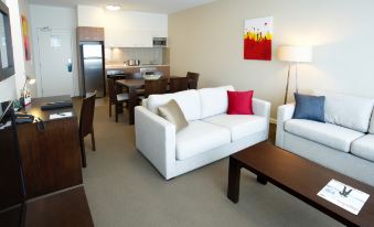 a modern living room with white furniture , including a couch and a dining table , is shown at Quest Mawson Lakes