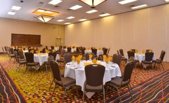 a large , empty conference room with multiple tables and chairs set up for an event at Ramada Plaza by Wyndham Sheridan Hotel & Convention Center