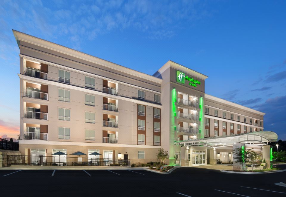 a large hotel with a green sign and a parking lot in front of it at Holiday Inn & Suites Arden - Asheville Airport