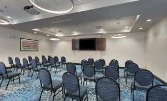 a conference room with rows of chairs arranged in a semicircle and a tv mounted on the wall at Holiday Inn & Suites Arden - Asheville Airport