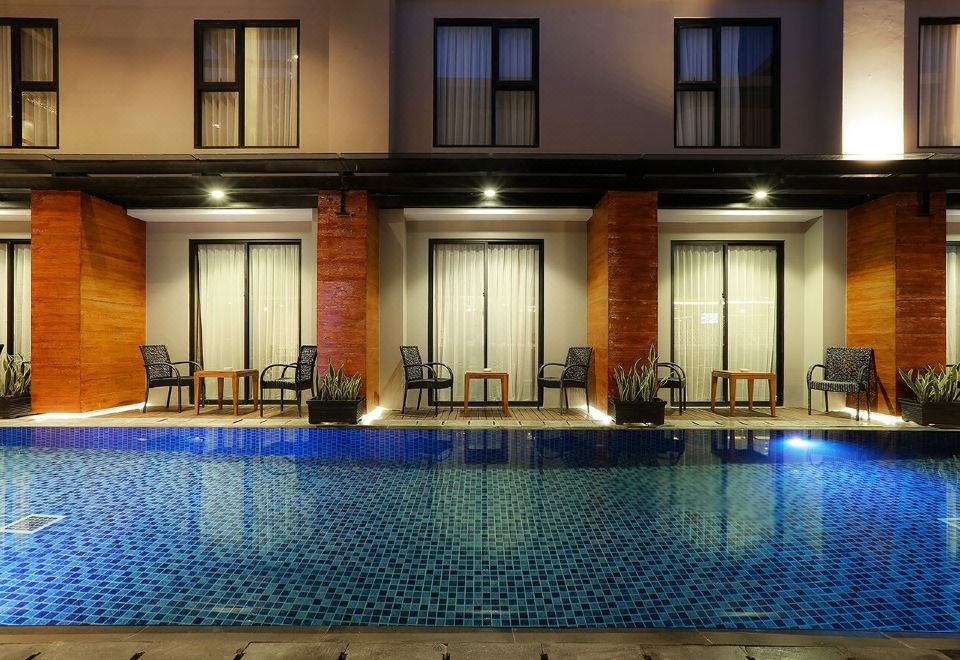 a large swimming pool is surrounded by chairs and tables in front of a building at Swiss-Belinn Timika