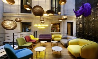 a colorful living room with a variety of chairs and couches arranged around a coffee table at Hotel The Public - Special Category