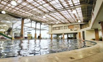 an indoor swimming pool surrounded by a glass ceiling , allowing natural light to fill the space at Hotel Cianjur Cipanas