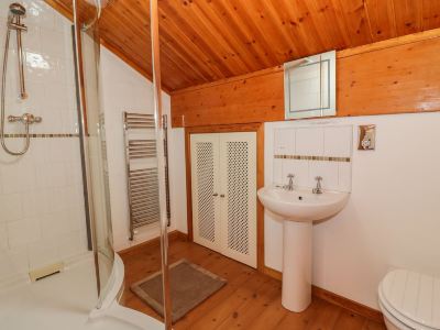 a bathroom with wooden walls , a sink , and a toilet , as well as a shower area at Moon Face