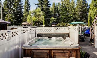 a wooden hot tub with a stone cover is situated in a backyard , surrounded by trees at Alpine Village Resort