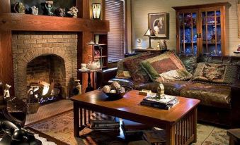 a cozy living room with a fireplace , antique furniture , and various items on the coffee table at Grady House Bed and Breakfast
