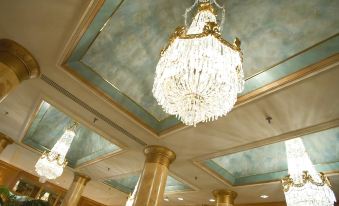 a grand chandelier hangs from the ceiling of a room with green walls and gold columns at The Saint Paul Hotel