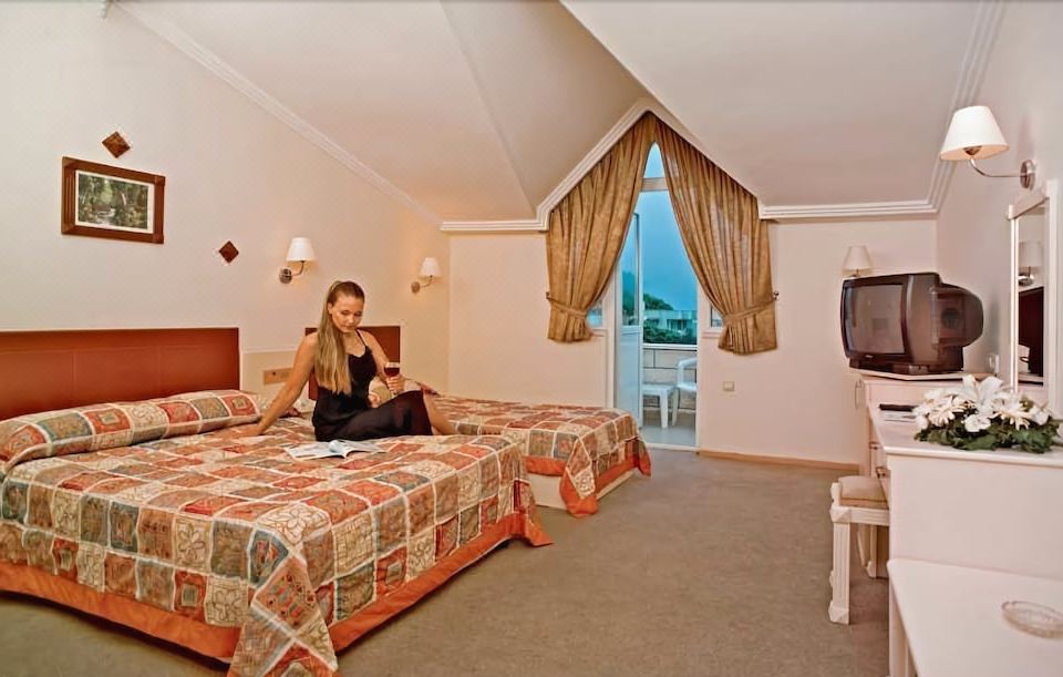 a woman is sitting on a bed in a hotel room with a view of the ocean at Havana Hotel