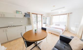 a living room with a dining table and chairs , a couch , and a television in a small apartment at Big4 Breeze Holiday Parks - Eildon