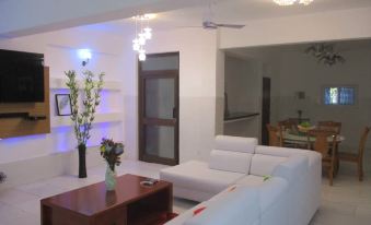 a modern living room with a white couch , wooden coffee table , and blue light above the couch at Luxury Apartment