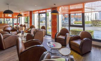 a spacious living room with several leather chairs and couches arranged in a comfortable seating area at Ibis Styles Lille Marcq-en-Baroeul