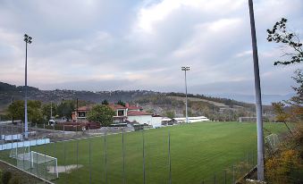 a grassy field with a soccer goal in the middle , surrounded by a chain link fence at Mythos