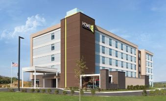 a large hotel building with a brown and white facade , surrounded by grass and trees at Home2 Suites by Hilton Harrisburg North