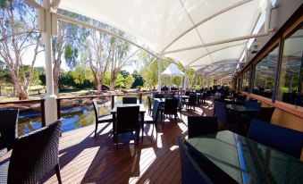 a large outdoor dining area with multiple tables and chairs under a canopy , providing shade and a pleasant atmosphere at The Kooralbyn Valley