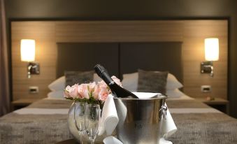 a hotel room with a bed , a tray of champagne and a bottle of champagne on it , and two lamps at Hotel Princess