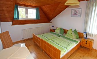 a cozy bedroom with wooden furniture , including a bed and desk , under a sloping ceiling at Frank