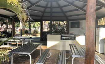a large outdoor patio area with multiple benches and tables , creating a pleasant outdoor dining area at BIG4 Hervey Bay Holiday Park