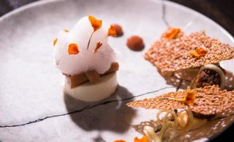 a plate with a small dessert made of white foam , surrounded by various toppings and garnishes at The Twelve Hotel