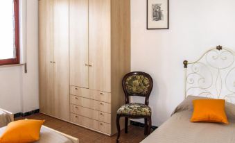 a cozy bedroom with wooden furniture , including a wardrobe and two beds , and orange cushions on the headboards at Cristina